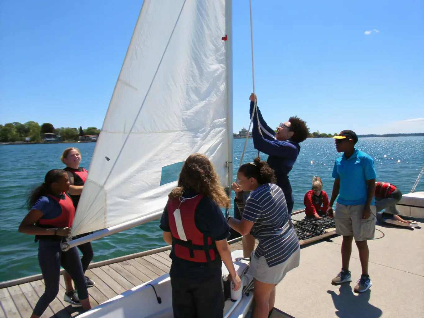A group of young sailors participating in a sailing lesson, showcasing teamwork and skill development.